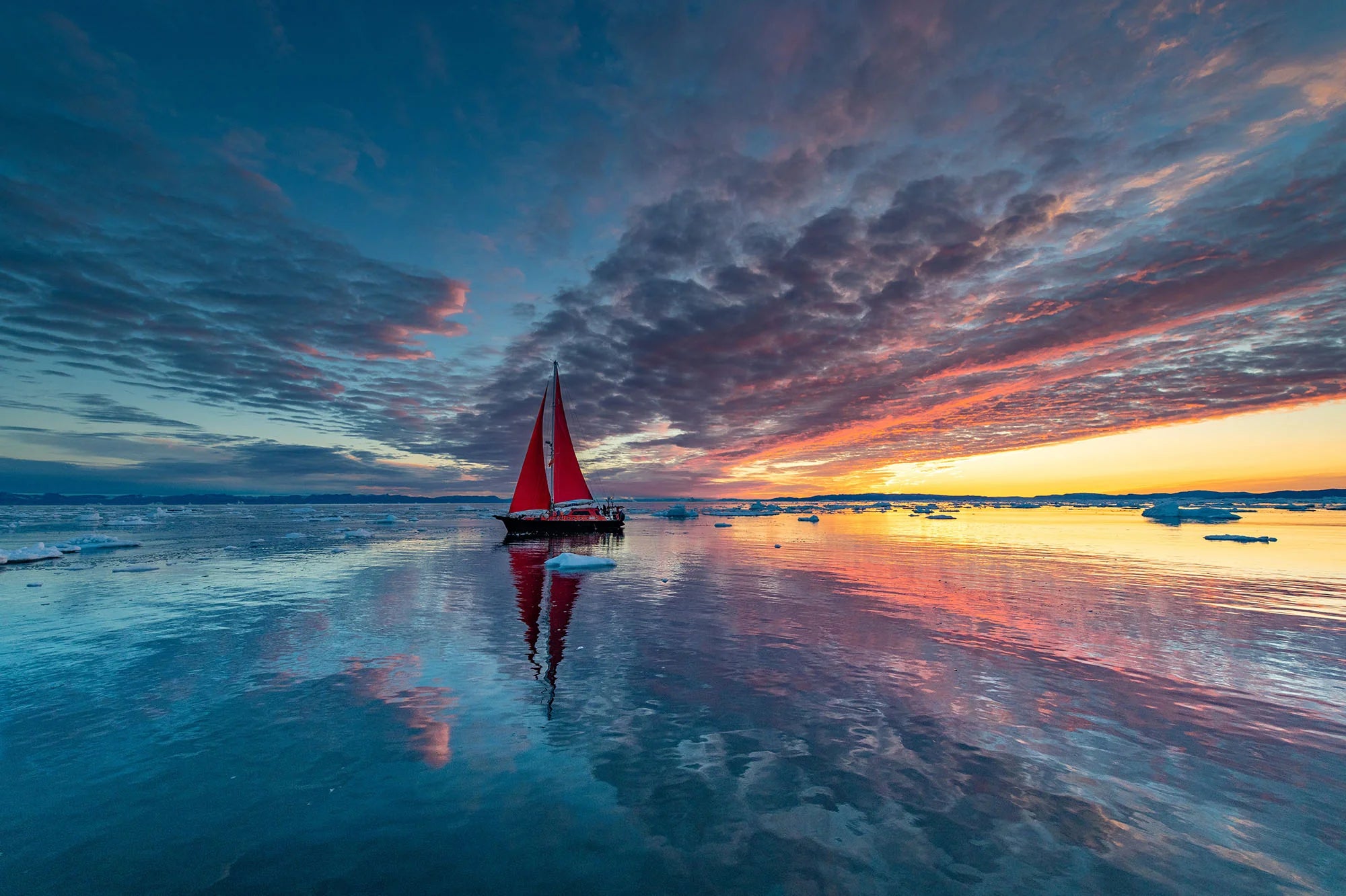 Sailboat on icy water at sunset