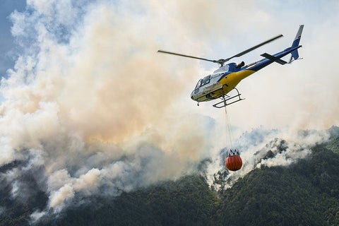 A helicopter carrying a bucket deliver water for forest fire