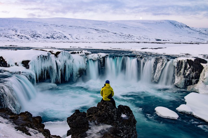 hiker overlooking winter waterfall