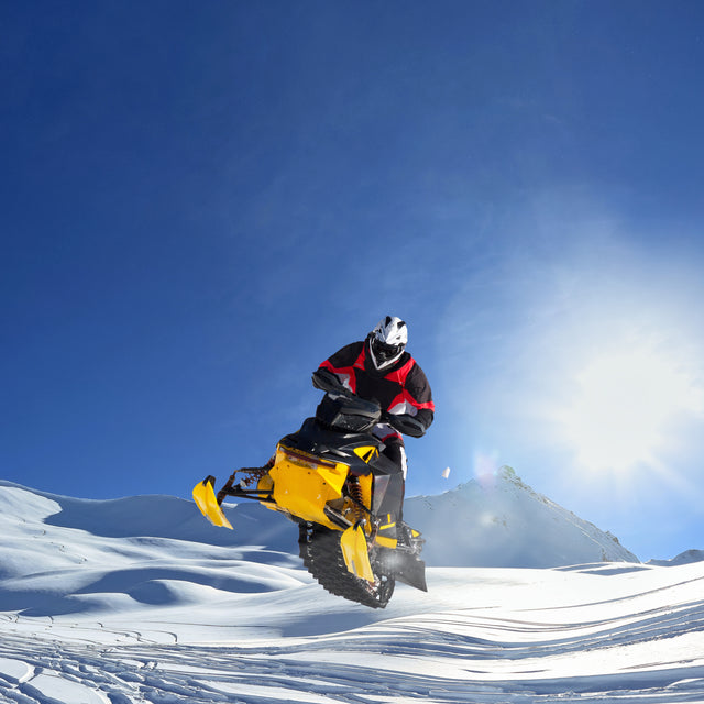 Person snowmobiling through a snowy forest