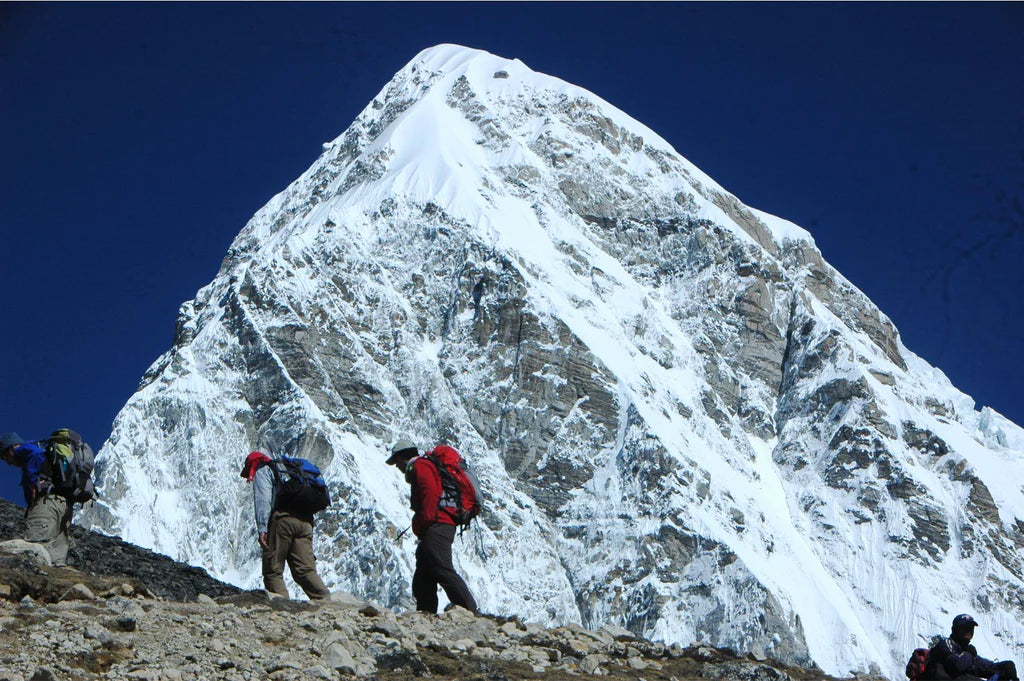 Two trekkers on their way up to Everest Base Camp with Mt. Pumori looming behind
