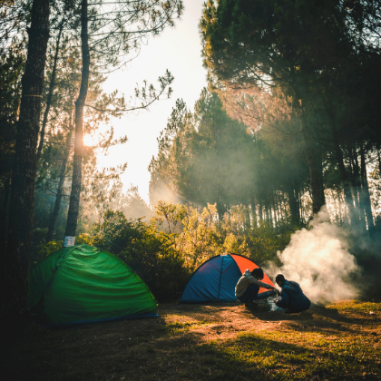 Campsite with two tents and two people by the fire