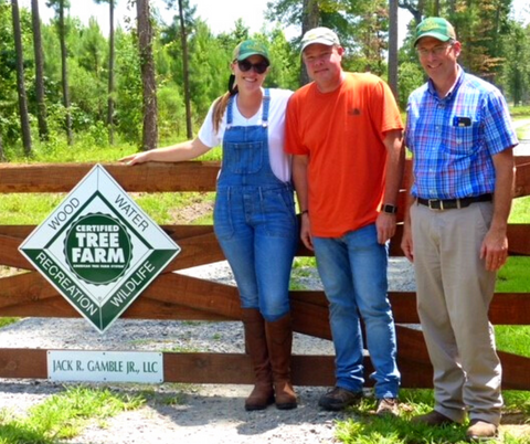 People standing next to the Certified Tree Farm sign