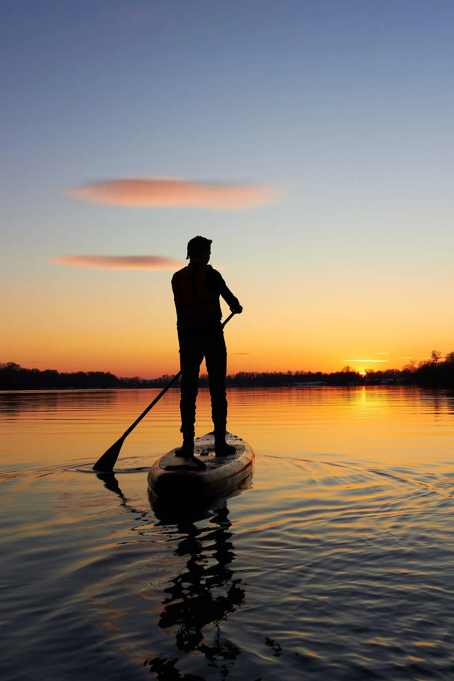 Man on stand-up paddleboard on the water at sunset