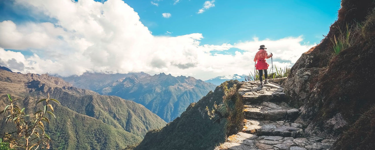 A female hiker walking on the famous Inca trail of Peru with walking sticks