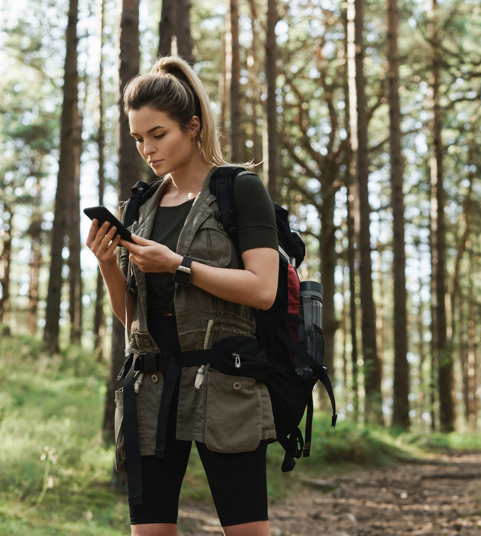 A hiker checking her phone in the forest