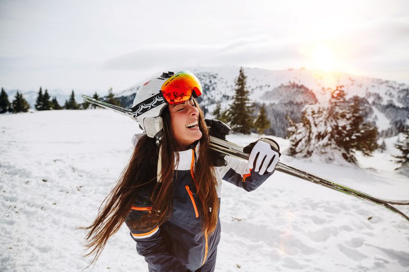 Woman laughing while holding skiis